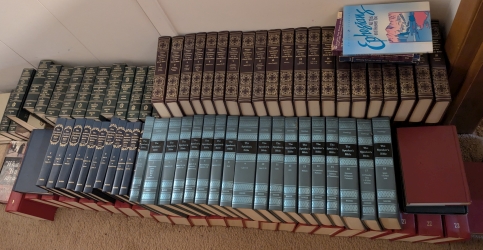 Close-up of Bible commentaries and study books stacked along a wall, some still without a proper shelf.